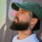 Mann trägt grüne Café NINI Cap im Vintage Wash Look, Seitenansicht vor Graffiti-Wand, lässiges Herren Lifestyle Lookbook