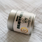 Nahaufnahme der silbernen NINI Matcha Dose Ceremonial Grade 30g liegend auf weißem Stoff, detailliertes Etikett mit NINI Matcha Logo und goldenem „Matcha in Town" Stempel sichtbar