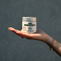 Silberne NINI Matcha Dose Ceremonial Grade 30g wird auf einer Hand präsentiert, Produktbild vor dunkelblauem Hintergrund mit sichtbarem NINI Matcha Etikett